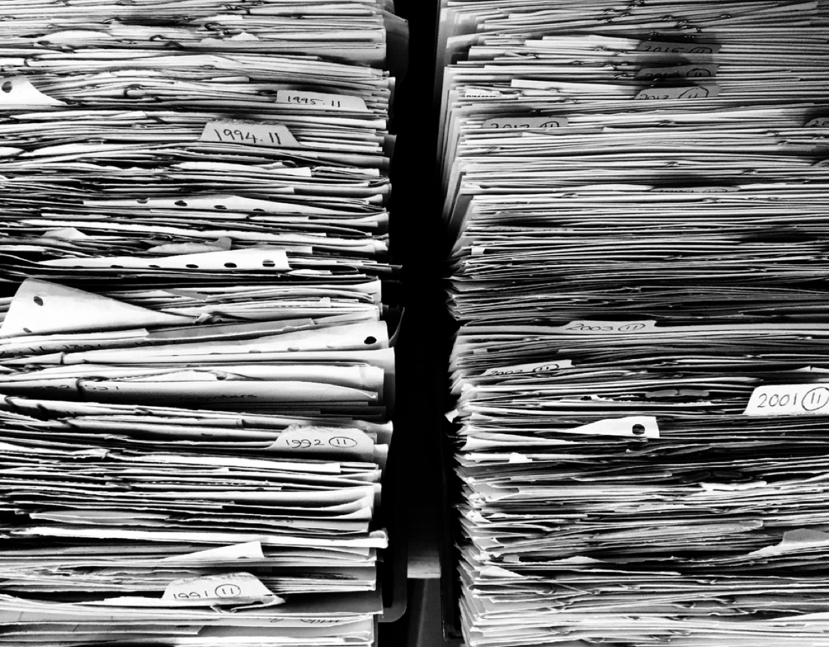 Faldoni e documenti cartacei accatastati in un archivio