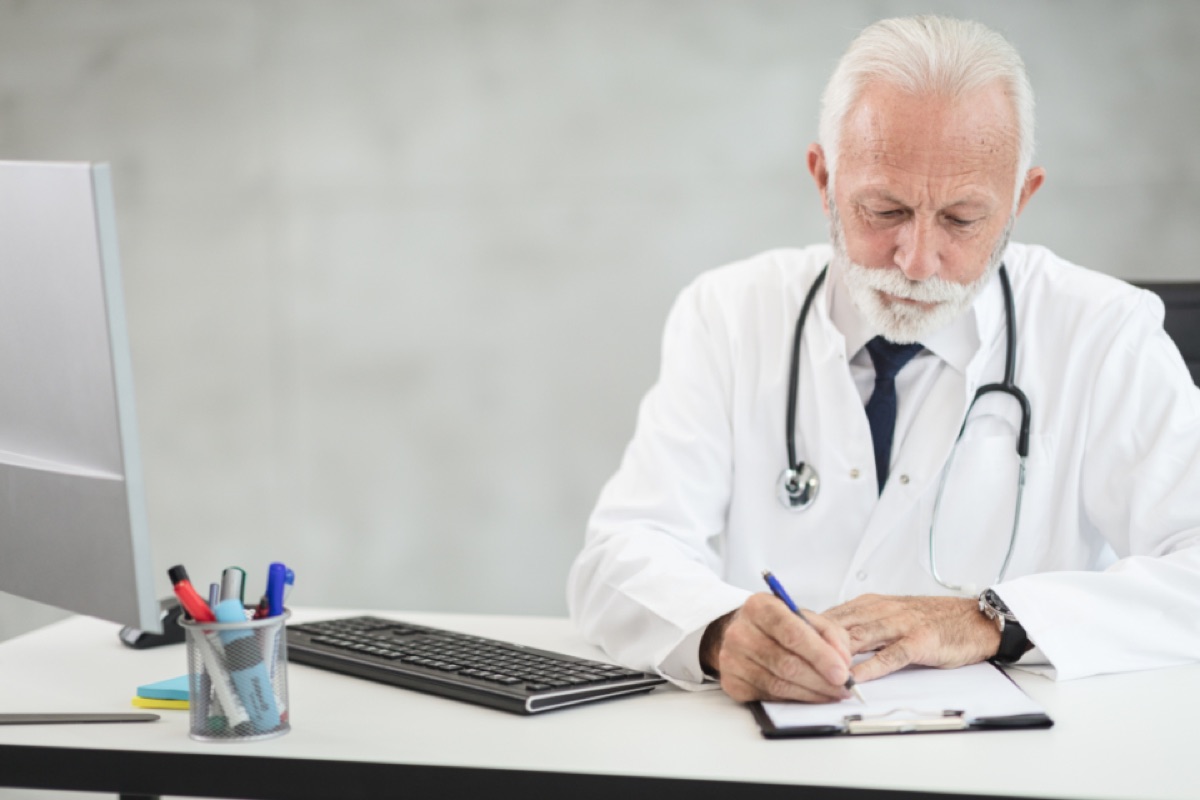 Medico alla scrivania mentre compila un documento